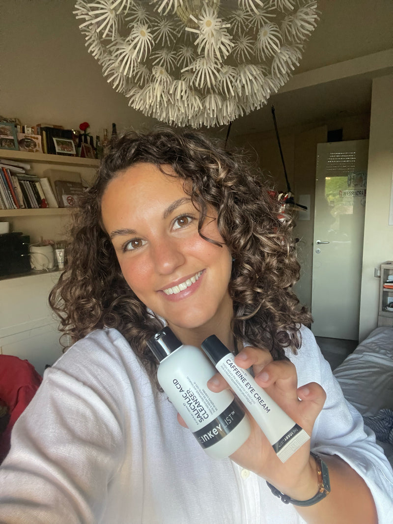 A woman holding a bottle of Salicylic Cleanser and Caffeine Eye Cream to her face