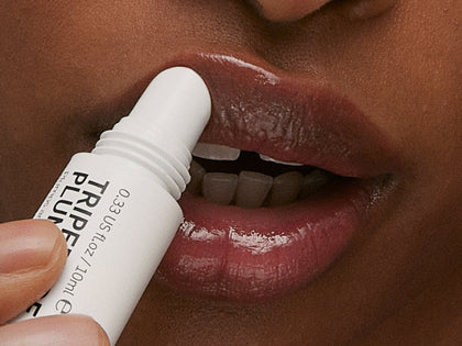 Model applying lip shade in Berry
