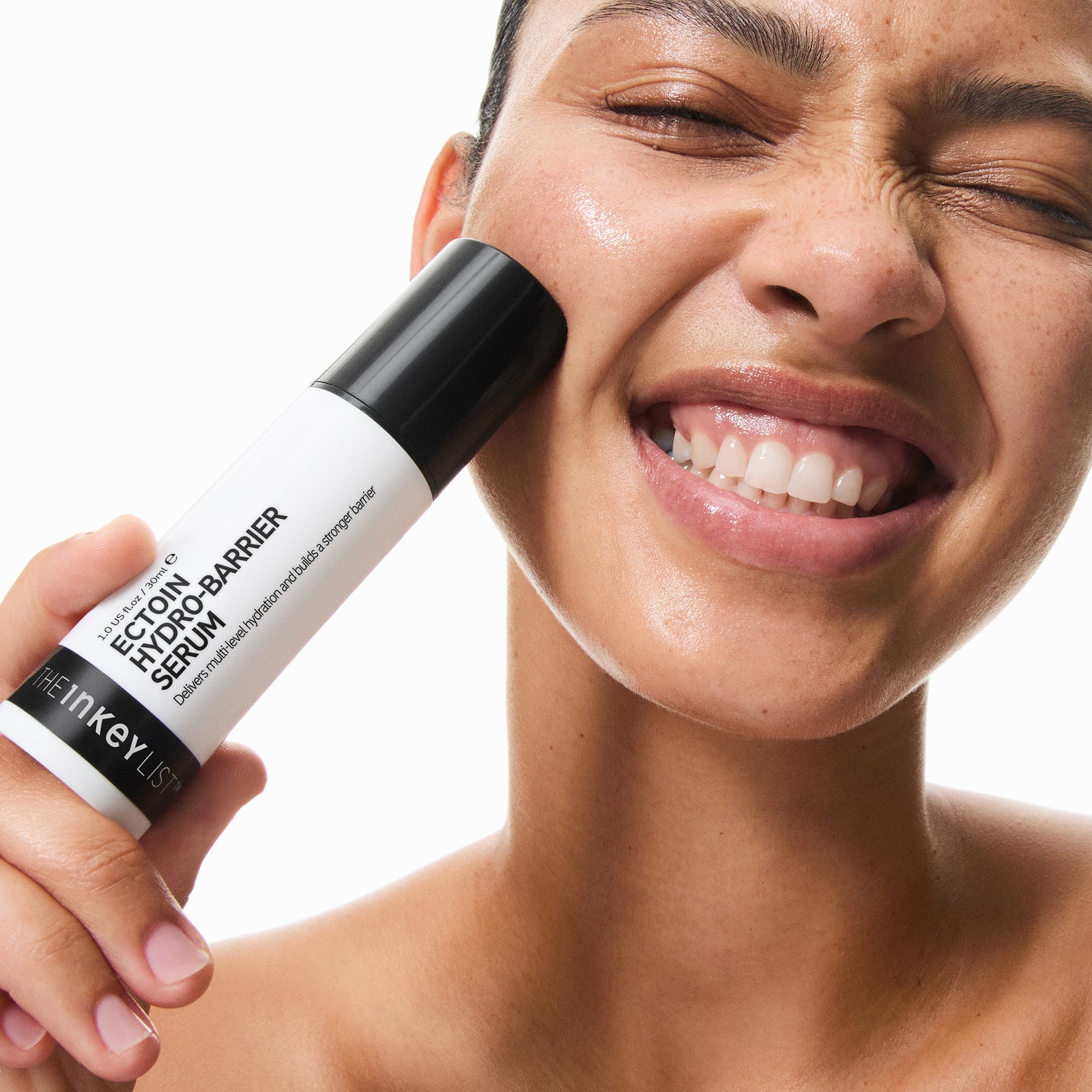 Woman applying a sEctoin Hydro-Barrier Serum to her face with a white background