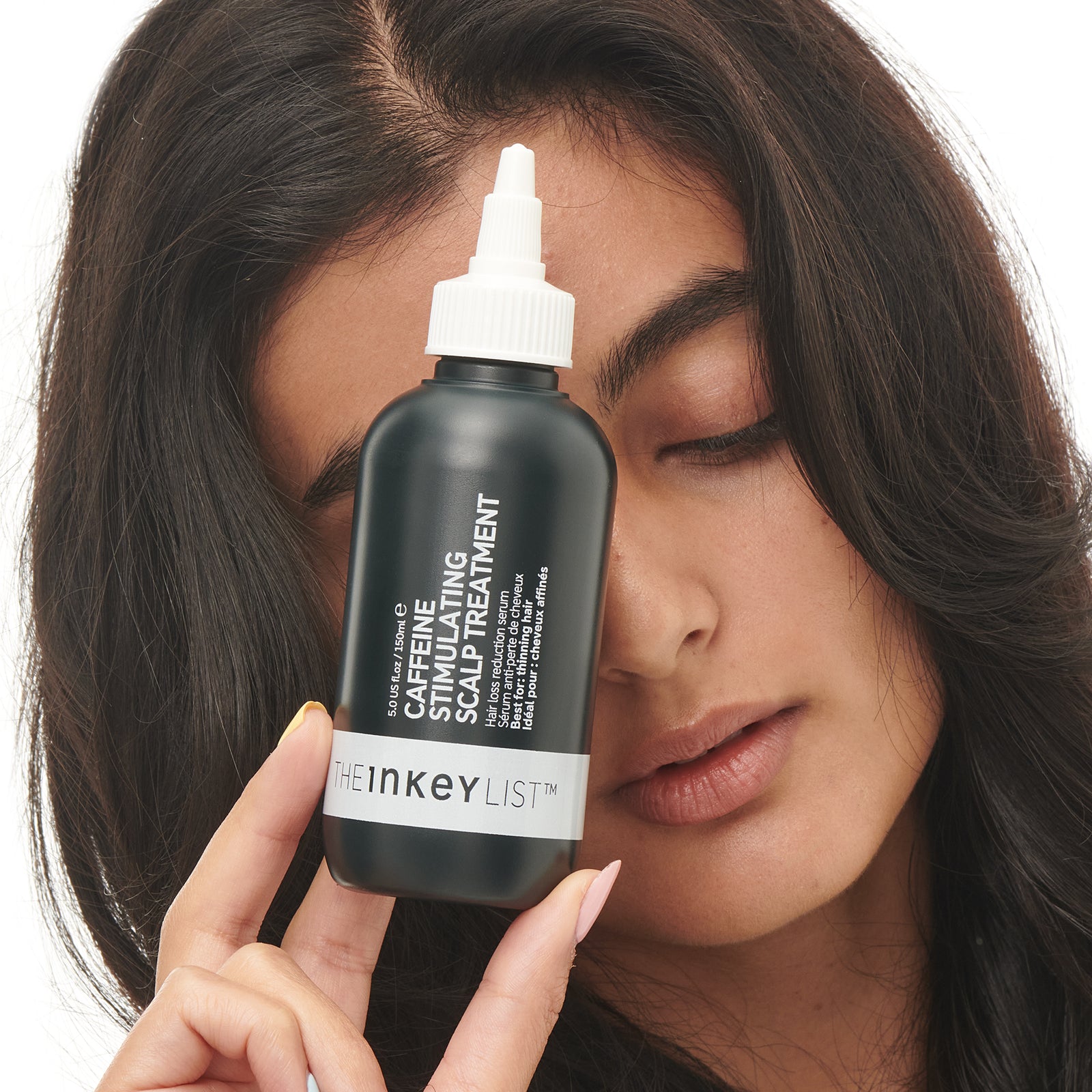 Caffeine stimulating scalp treatment with model holding the bottle