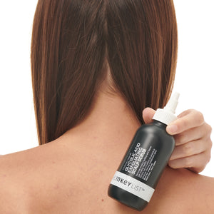 Glycolic Acid Exfoliating Scalp Scrub bottle with model holding it over her shoulder