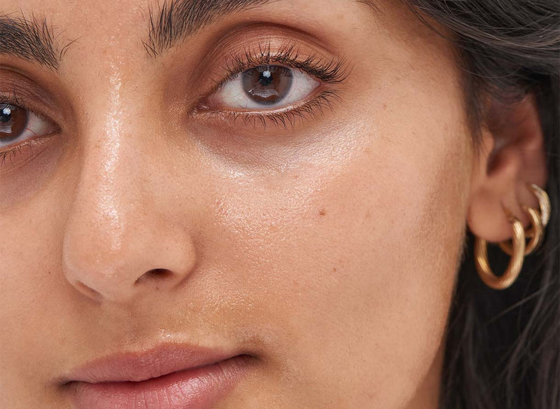 Close-up of hydrated, plump-looking skin on a bare face with soft natural light and visible bounce and dewiness.