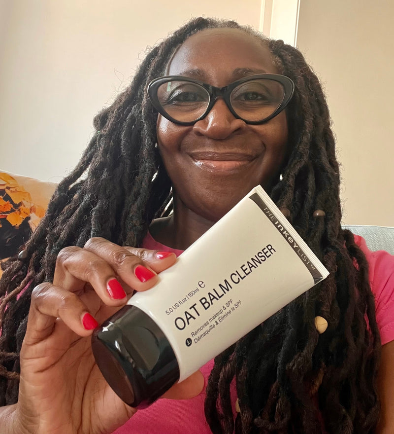 A woman holding a bottle of Oat Cleansing balm to her face