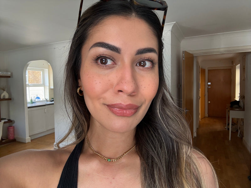 A woman with sunglasses and a necklace taking a selfie style photo