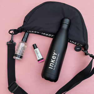 Black cosmetic bag with Inkey brand products on a pink background