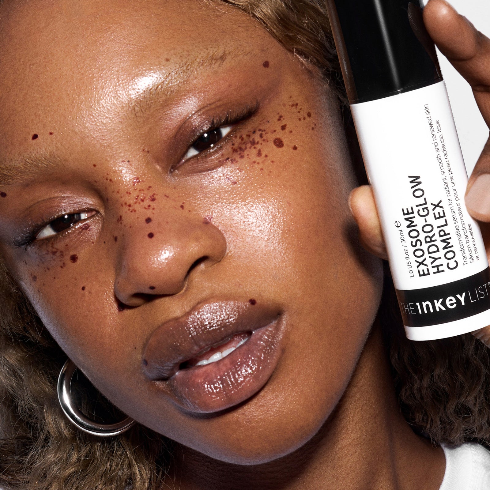 Person holding a skincare product close to their face