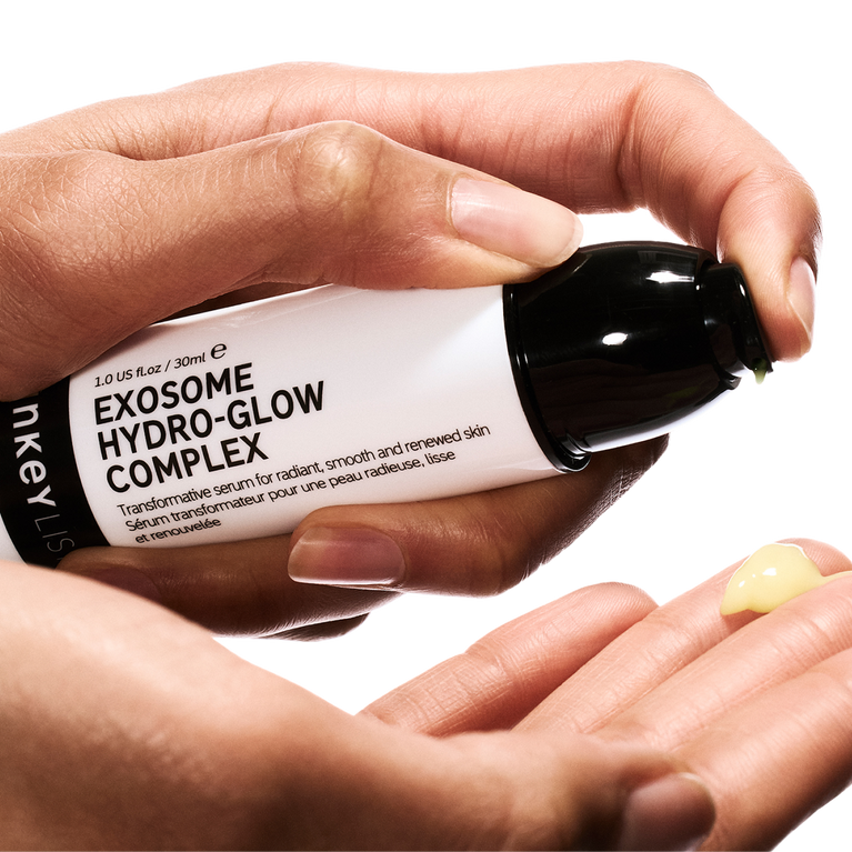 Hand holding a skincare serum labeled 'Exosome Hydro-Glow Complex' by nkey.
