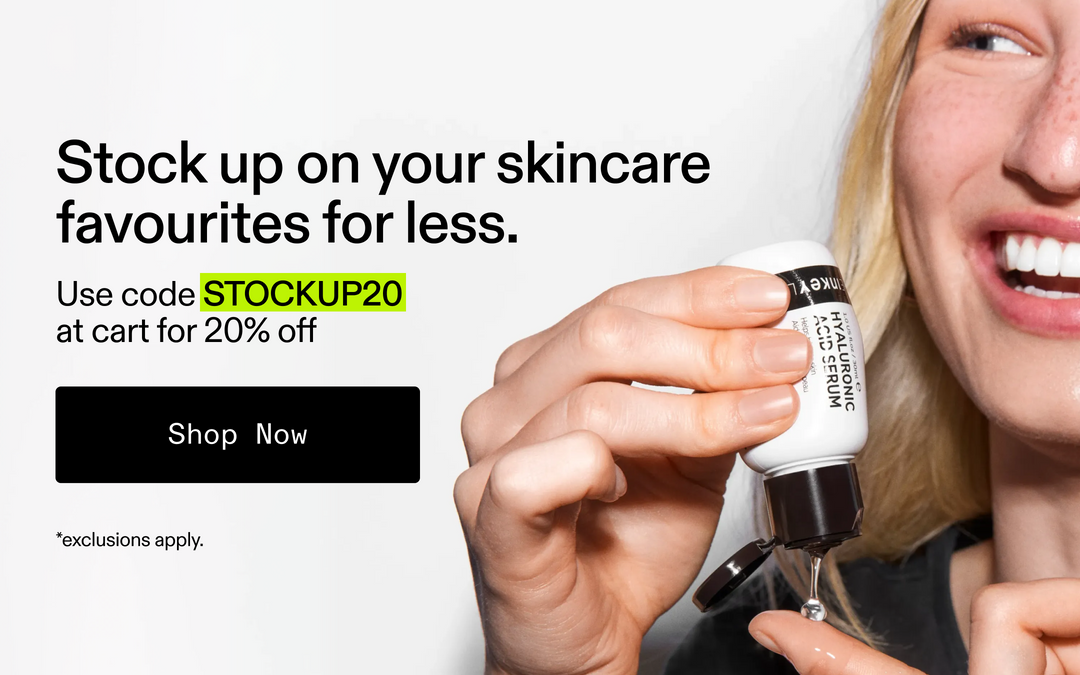A promotional skincare ad showing a woman smiling while holding a small white bottle of Hyaluronic Acid Serum, with text on the left offering a discount code and a black 'Shop Now' button.