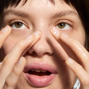 Close-up of a person with hands near their face, focusing on the eyes.