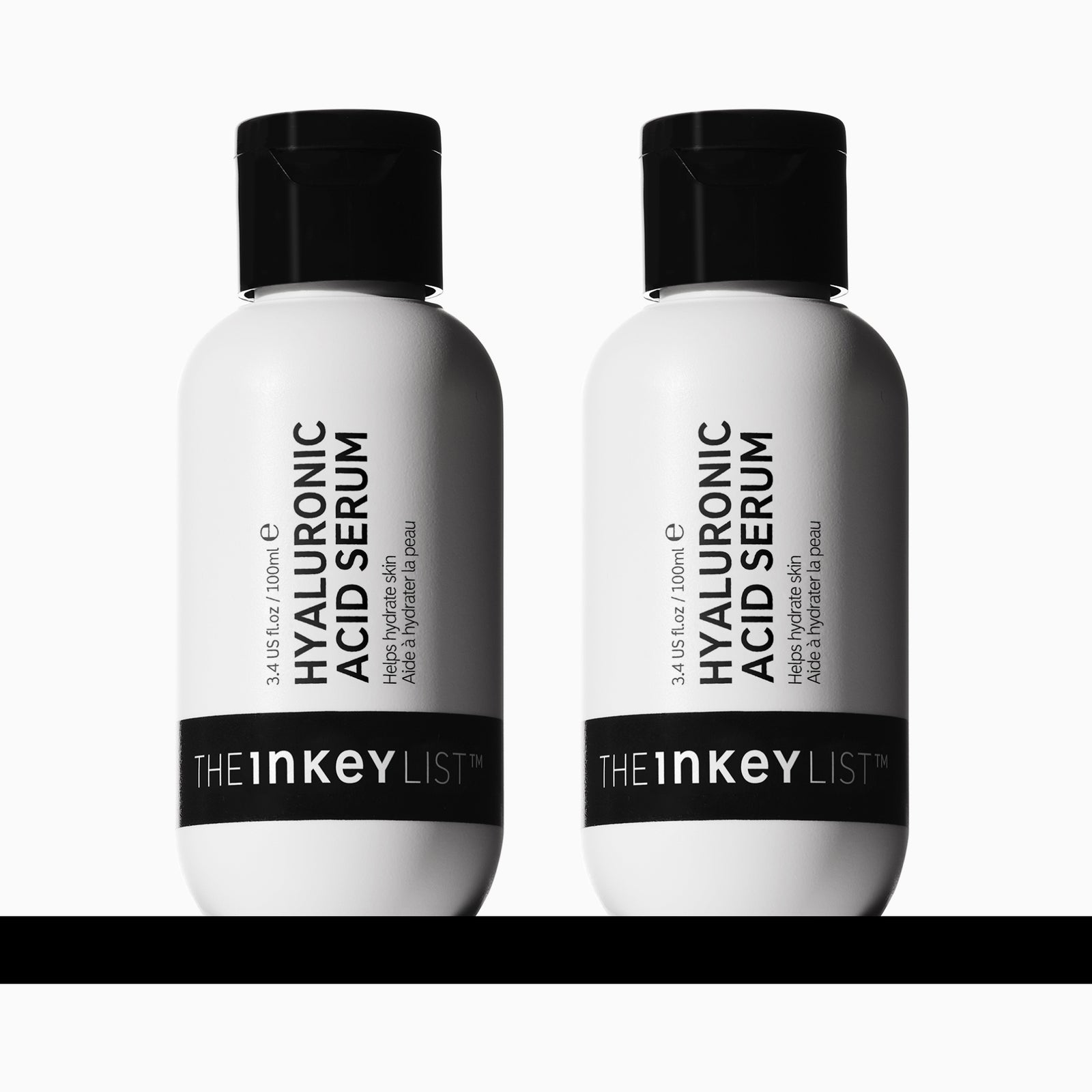 2 Bottles of The Inkey List Hyaluronic Acid 100ml Serum side by side on a black horizonal line.