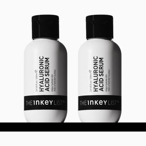 2 Bottles of The Inkey List Hyaluronic Acid 100ml Serum side by side on a black horizonal line.
