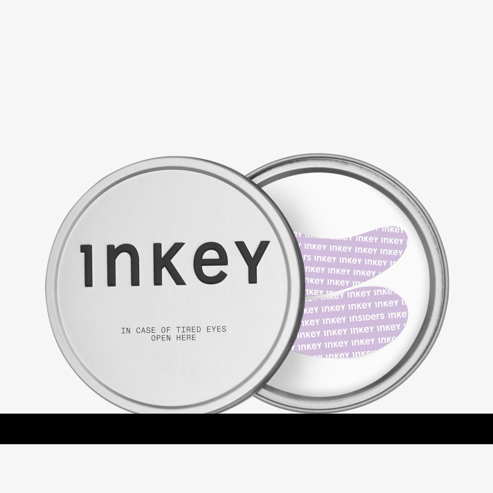 A round silver metal tin for Inkey Reusable Eye Patches on a white background, one showing the front lid with black text and the other showing the inner lid with purple text.