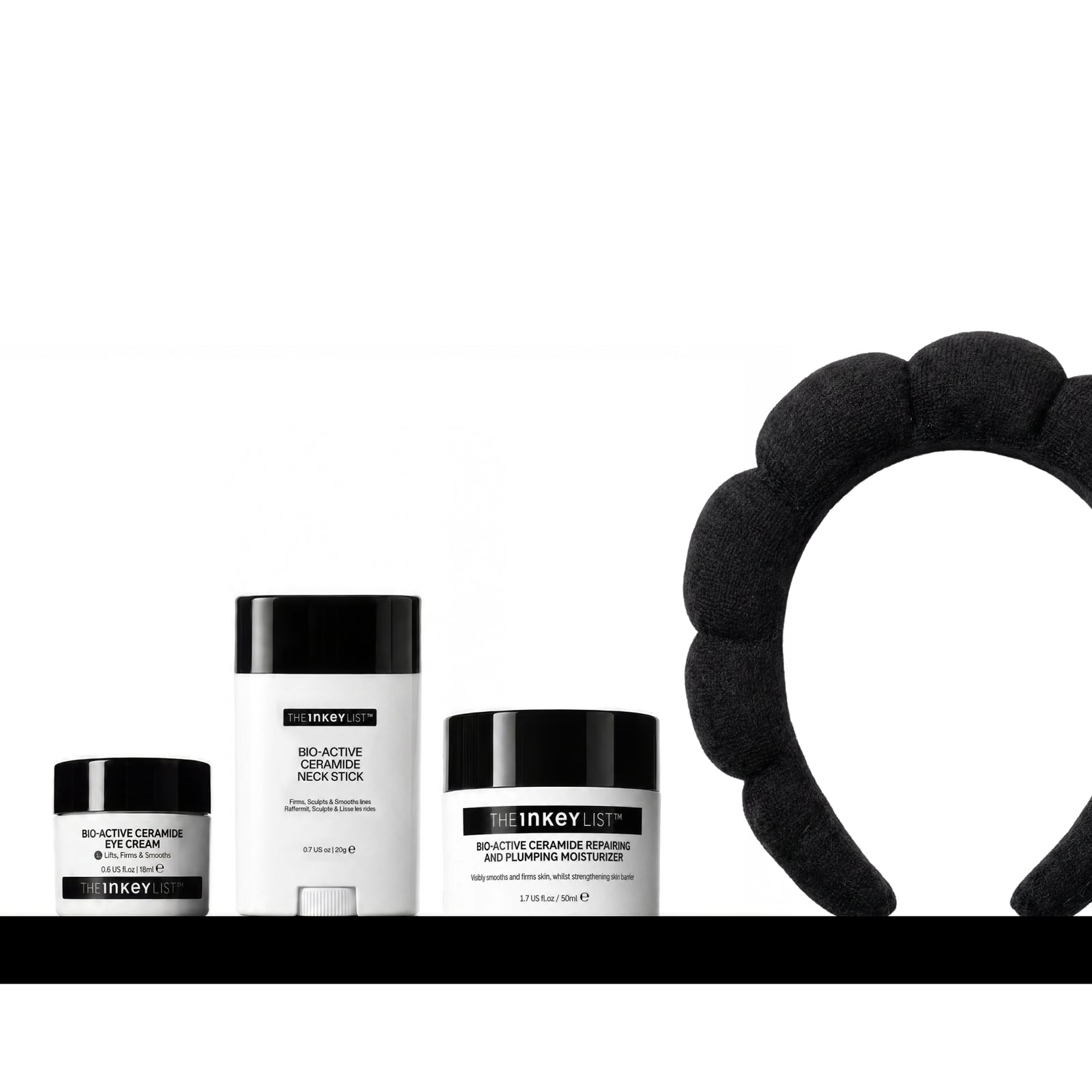 A skincare set from Heiney List on a white background, featuring a black silicone headband on the right, and three black-and-white containers on the left: a jar of Bio Active Ceramide Eye Cream, a stick of Bio-Active Neck Stick, and a jar of Bio-Active Ceramide Moisturizer.