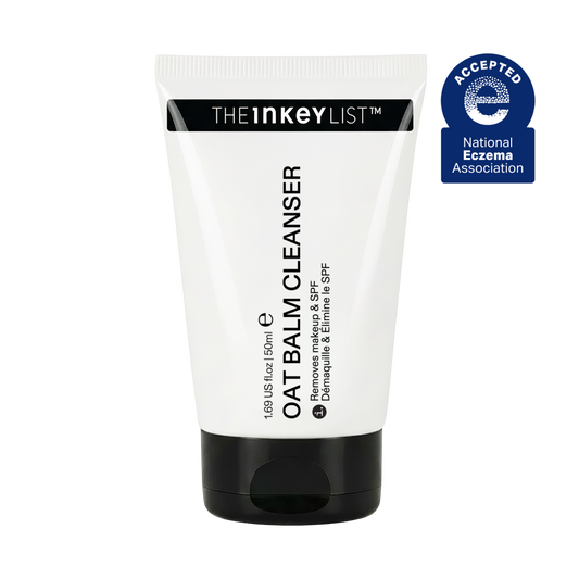 A white squeeze tube of The Inkey List Oat Balm Cleanser with a black cap, shown on a plain white background with a blue National Ecocoma Association seal in the top right corner.