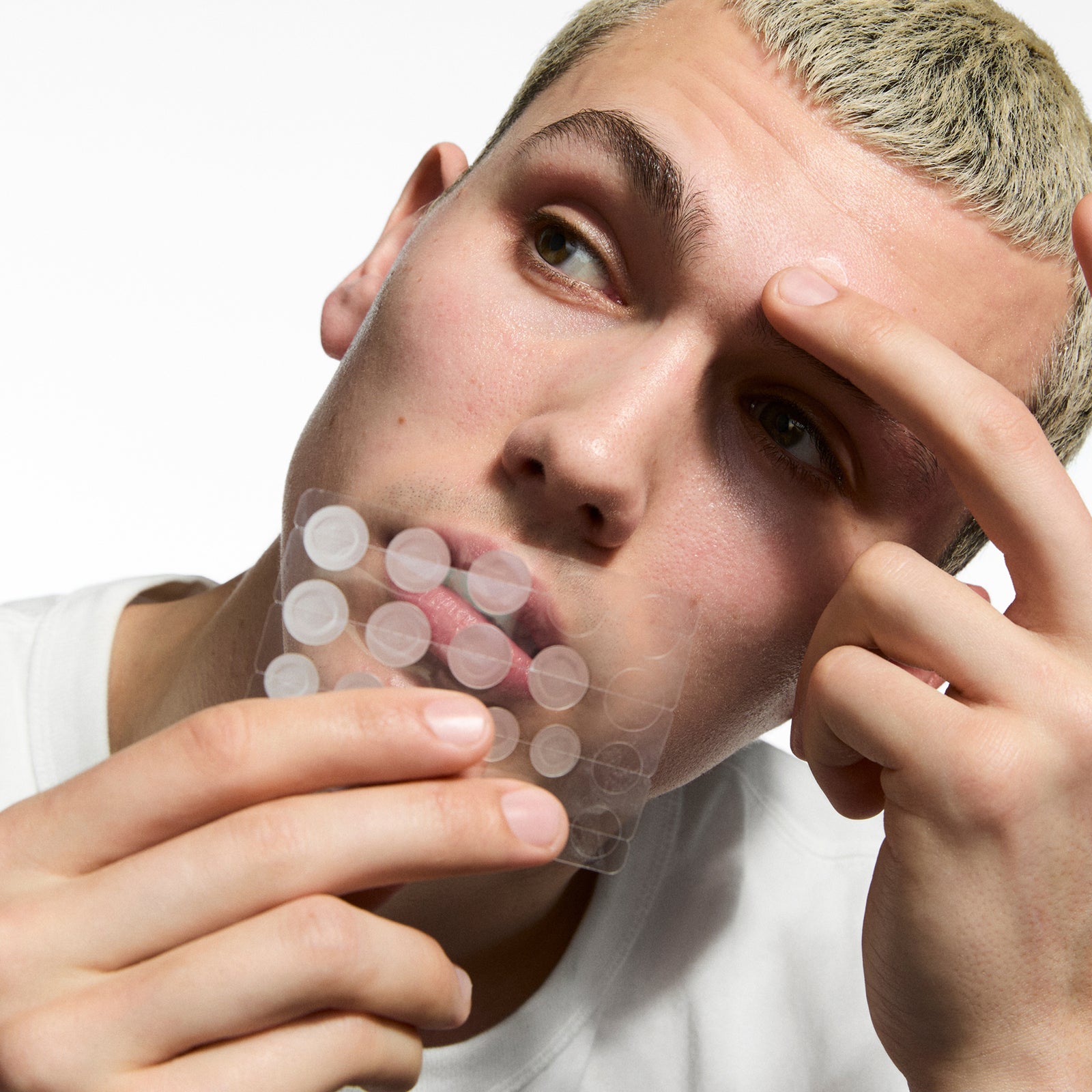 Person holding Hydrocolloid Invisible Pimple Patches, against a white background.