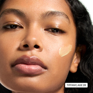 Close-up of a woman's face with a makeup product applied to her cheek, labeled 'Tiffany, Age 28'.