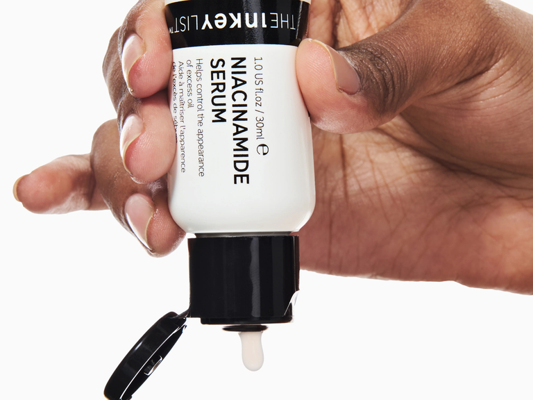 Hand holding a skincare serum bottle with visible brand name.
