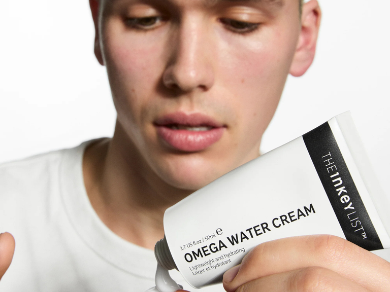 Person holding a tube of 'Omega Water Cream' by The Inkey List