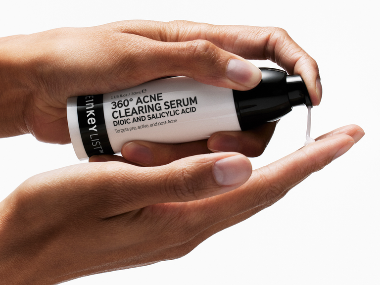 Hand holding a bottle of 360 Acne Clearing Serum with visible text.