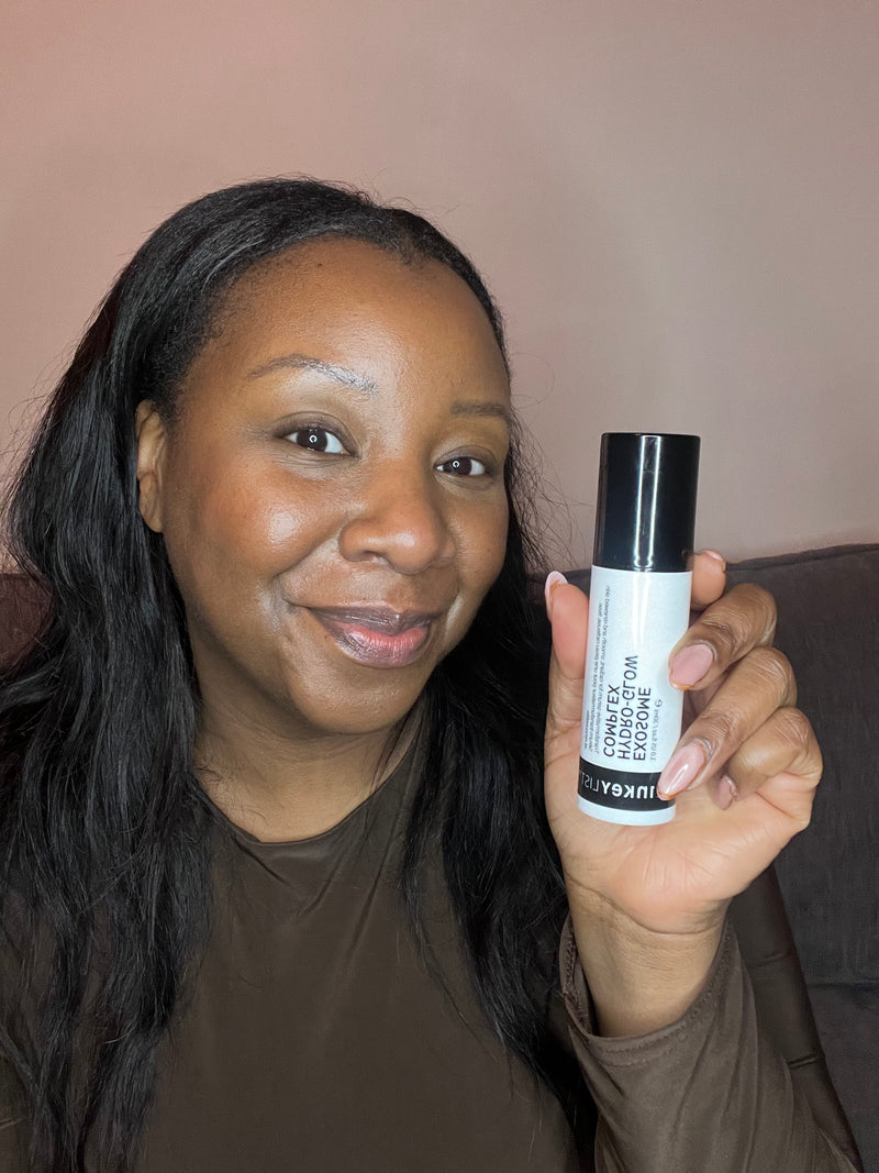 A woman holding a bottle of Exosome Serum to her face 