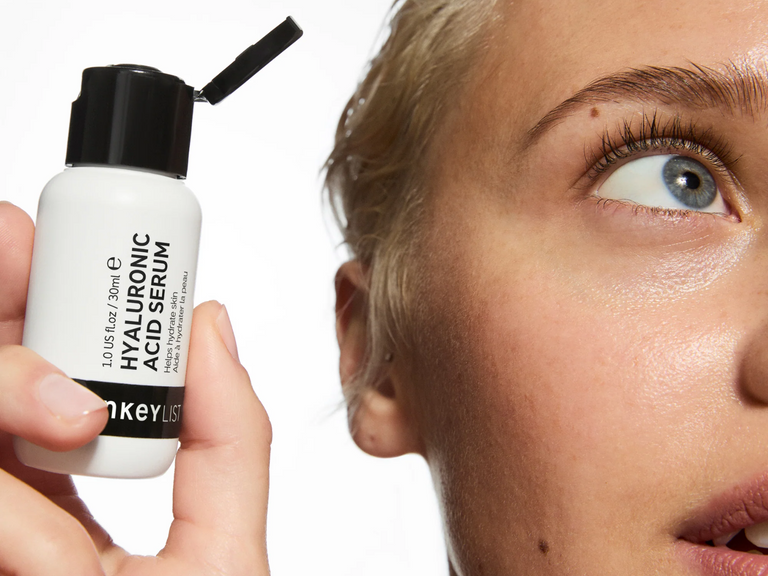 Person holding a bottle of Hankey Liss Hyaluronic Acid Serum close to their face.