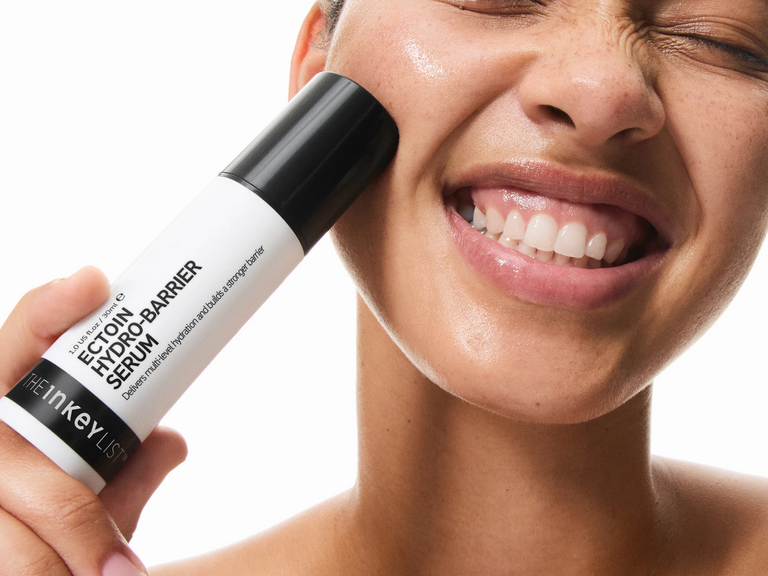 Person applying a skincare serum to their face with a close-up of the product.
