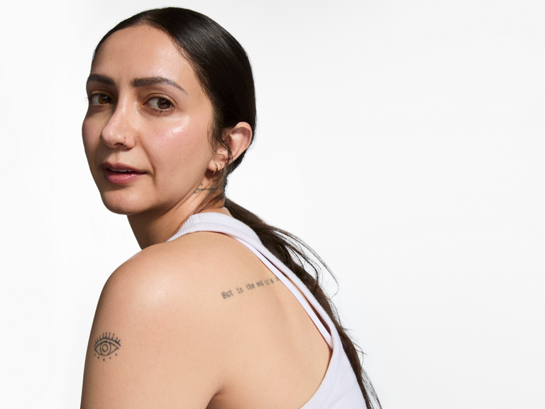 Woman with tattoos on her arm and shoulder against a white background