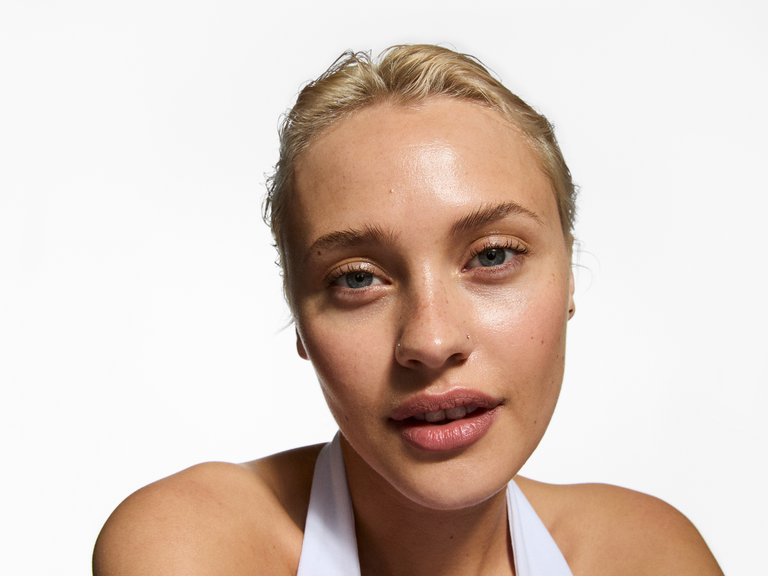 Woman with blonde hair and blue eyes against a white background