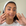 Woman applying a skincare product to her face with a white headband on.