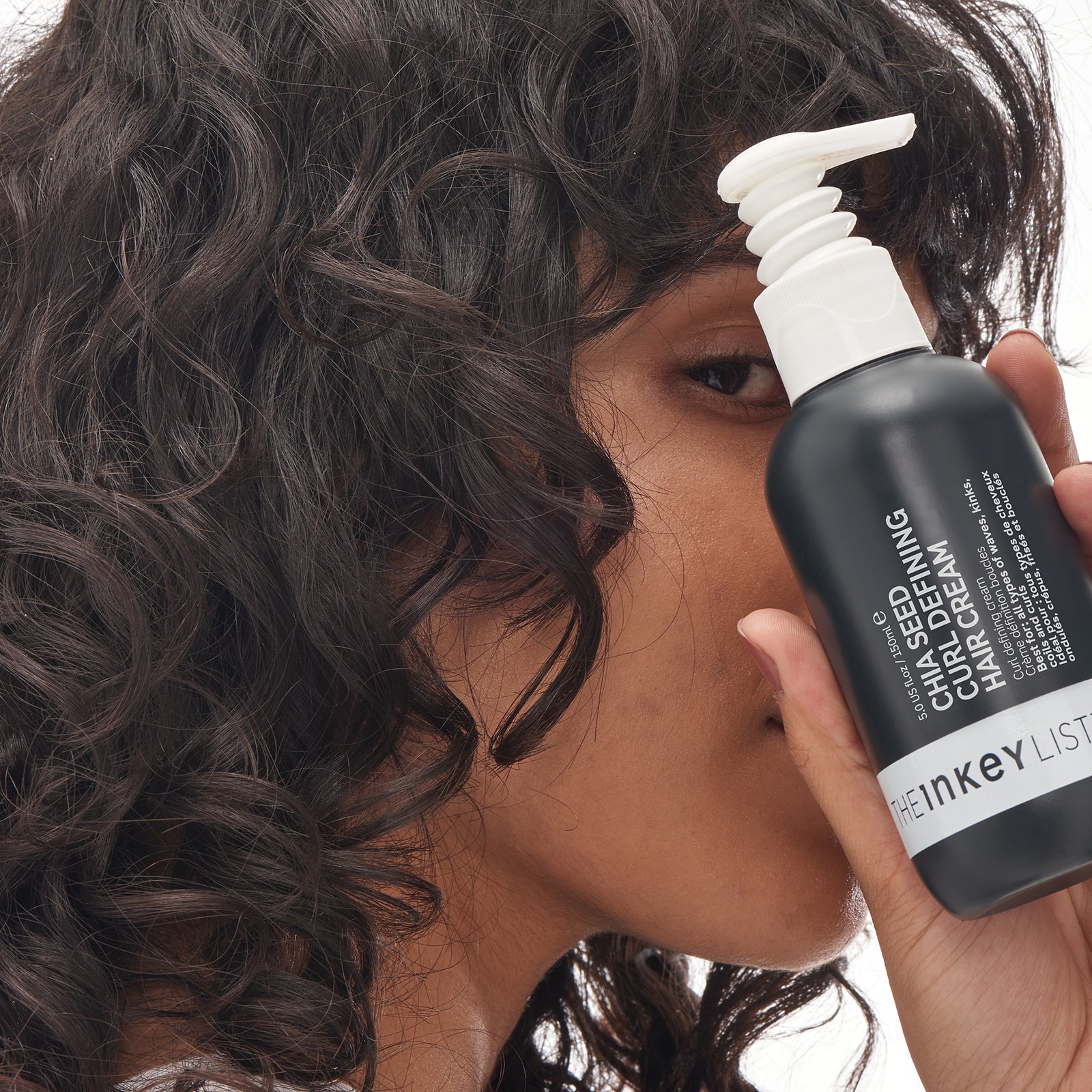 Model holding a bottle of the Chia seed curl defining hair treatment