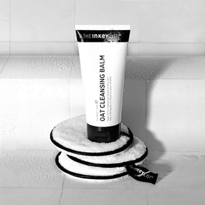 Image of the Oat Cleansing Balm sitting on top of a stack of 3 Reuseable Cotton Pads in a white tiled bathroom as part of a great cleansing routine