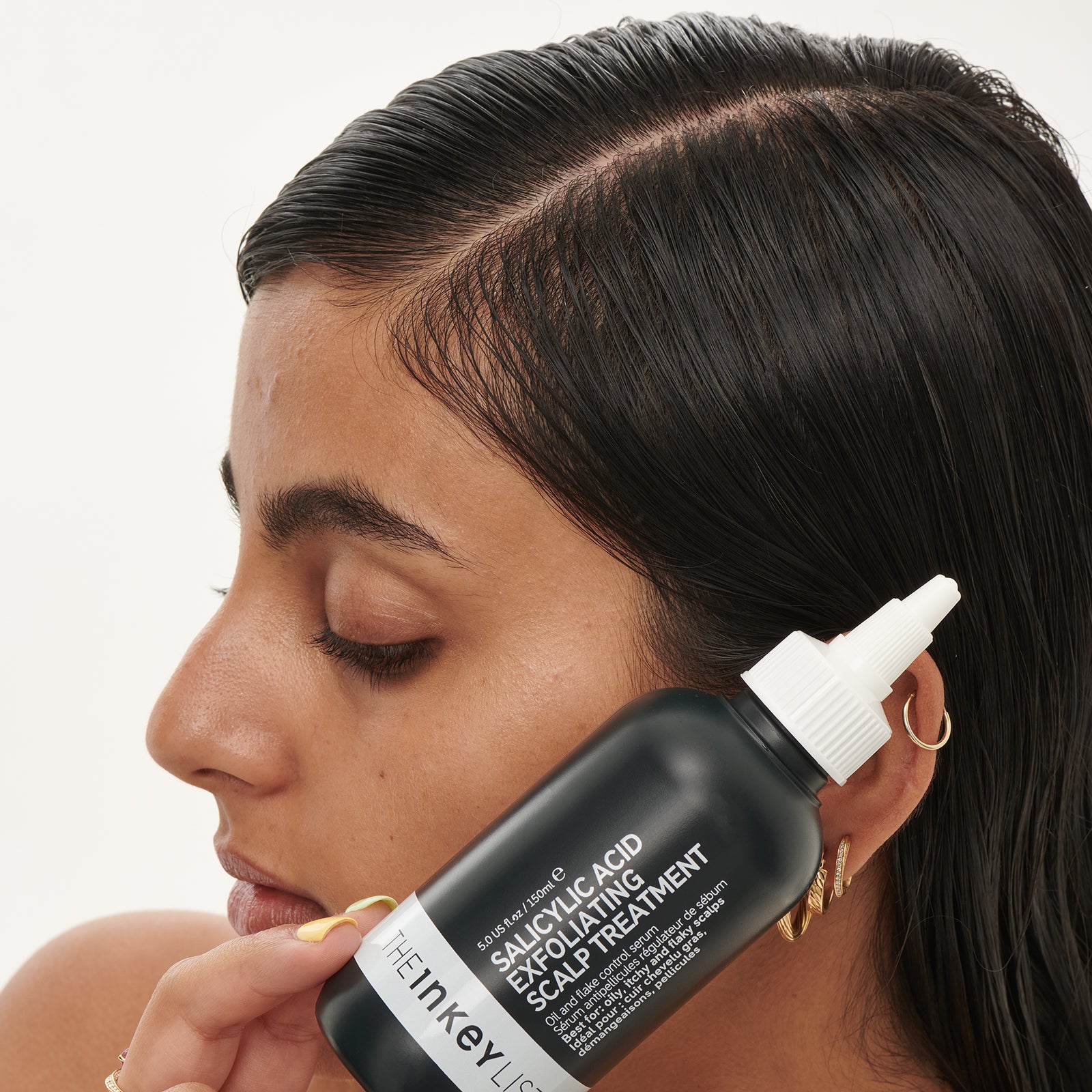 Model holding Salicylic Acid bottle as part of the Clean & Healthy Scalp Duo